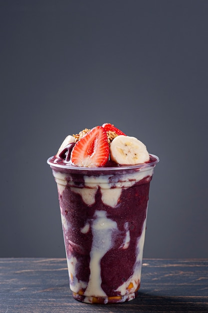 Brazilian frozen açaí in a plastic cup with condensed milk, banana